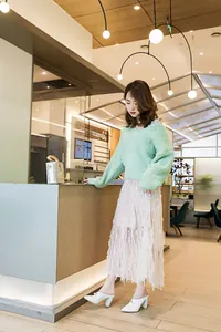 Stylish white pointed-toe block heel mules with pearl details worn in a cafe.