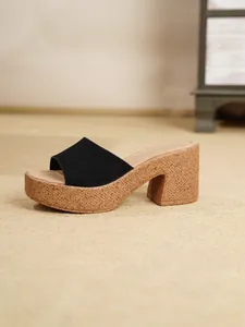 Primer plano lateral de sandalias de plataforma en ante negro con tacón de bloque de corcho