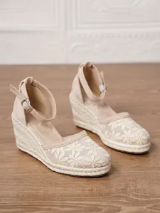 Detalle de sandalias de cuña beige para mujer con bordado de flores y suela de fibra de yute.
