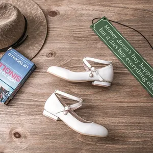 Elegant white Mary Jane flat shoes with decorative pearl charms on cross straps