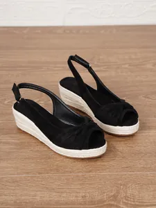 Detail shot of black peep-toe wedge sandals with braided jute soles and ankle straps.
