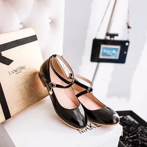 Close-up of girls' black patent Mary Jane shoes with delicate pearl charm detail