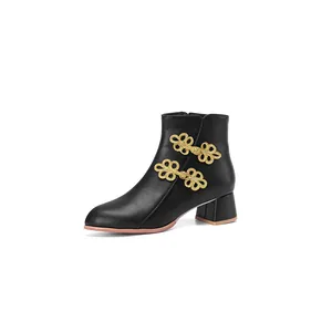Elegant side view of a black ankle boot featuring ornate gold-toned frog-knot closures
