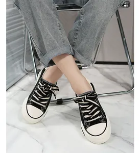 Detailed view of women's black and white platform canvas sneakers worn with blue jeans