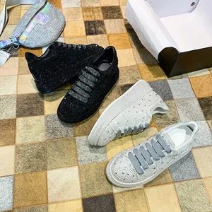 Close-up of sparkling black and white rhinestone sneakers on a textured checkered rug.