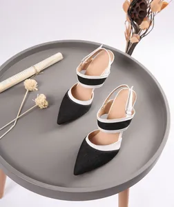 Detalle de sandalias de aguja de mezclilla en punta de estilo francés con ribete blanco.