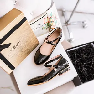 Elegant black patent leather Mary Jane shoes with a pearl charm buckle on white background