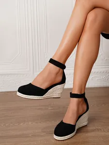 Detalle de sandalias de cuña de lona negra para mujer con tacón de esparto trenzado