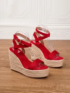 Detalle de sandalias con cuña de gamuza roja y plataforma de paja trenzada