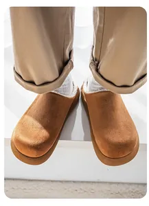 Detailed close-up view of tan suede winter slippers with warm white fleece lining