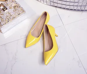 Detailed view of elegant bright yellow patent leather pointed-toe pumps on a marble floor