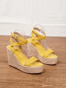 Vista detallada de sandalias con cuña de ante amarillo y suela de cuerda trenzada