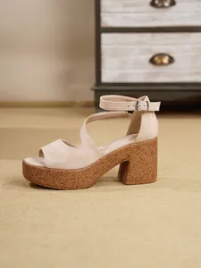 Detalle lateral de sandalias de plataforma en ante beige con tira al tobillo y tacón