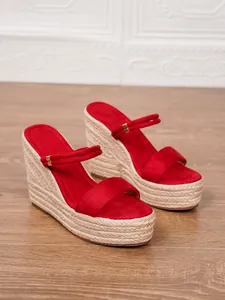 Vista lateral de sandalias de cuña en ante sintético rojo con plataforma de yute tejido moda