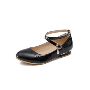 Close-up detail of black patent leather Mary Jane shoes featuring a pearl charm and strap