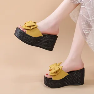 Modische gelbe Plateau-Keilsandalen mit Schleifendetail am Fuß eines Models.