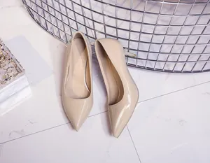Elegant beige patent leather pointed-toe stiletto pumps displayed on a marble surface.