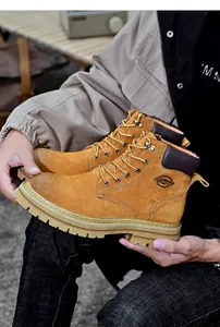 Vue détaillée de bottes de travail en cuir jaune tenues à la main montrant la texture