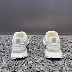 Detailed back view of white breathable mesh men's sneakers on textured grey gravel