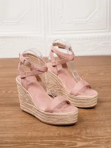 Vista lateral detallada de sandalias de cuña en ante rosa con plataforma de paja tejida