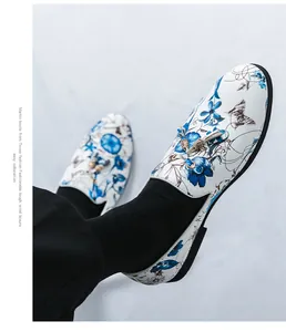 Close-up of men's white loafers featuring blue floral print and tassel details