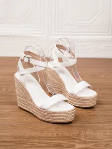 Detalle de sandalias de cuña tipo alpargata blancas con plataforma de cuerda trenzada.