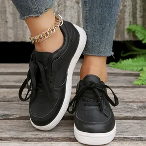 Nahaufnahme von schwarzen Damen-Sneakern mit weißer Sohle, getragen zu Jeans und Fußkette.