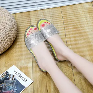 Detailopname van stijlvolle platte sandalen met strassteentjes en een neon groene binnenzool