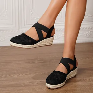 Detalle de alpargatas con cuña de encaje negro y suela de esparto trenzado natural