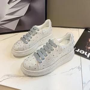Detailed macro view of white rhinestone-covered platform sneakers with wide grey laces