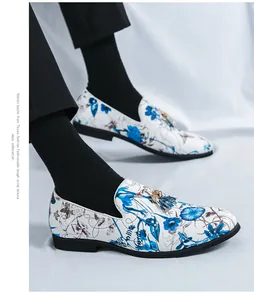 Detailed view of men's white slip-on loafers with blue floral pattern and tassels
