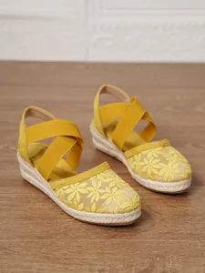 Sandalias de cuña amarillas con bordado floral, suela de yute y tiras elásticas.