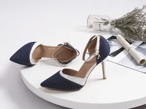 Close-up of denim pointed toe stiletto high heels with white trim and ankle strap