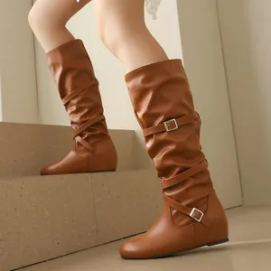 Detail of retro brown slouched mid-calf boots with decorative straps and buckles.