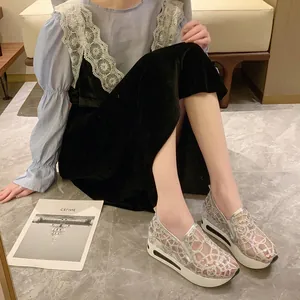 Detailed view of silver lace mesh platform sneakers worn by a model on marble floor.