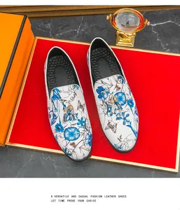 Detailed view of white men's loafers with elegant blue floral print and golden tassels