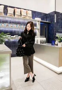 Elegant black pointed-toe block heel mules with a pearl detail worn by a fashion model