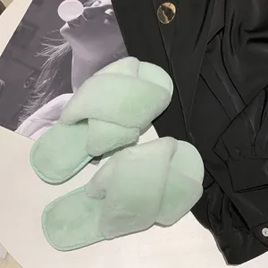 Mint green fuzzy cross-strap indoor slippers shown on a stylish lifestyle background