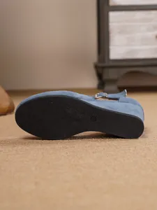 Detailansicht der strukturierten Gummisohle und des blauen Keilabsatzes dieser Sandale.