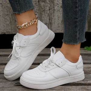 Detailansicht der weißen Plateau-Sneaker mit Schnürung, getragen von einem Model in Jeans.