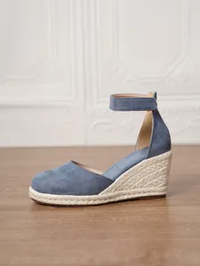 Elegante vista lateral de sandalias de esparto con cuña en ante azul y tacón de yute