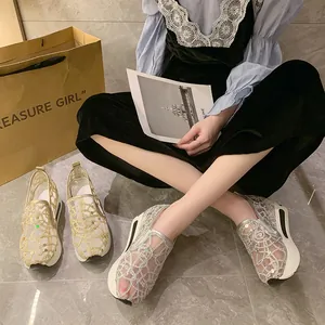 Close-up of lace mesh platform shoes with sequin details in silver and gold colors.