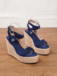 Detalle de sandalias con cuña de ante azul con suelas de plataforma de cuerda trenzada