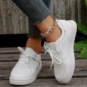 Detailansicht weißer flacher Sneaker kombiniert mit einer schicken Gold-Silber-Fußkette