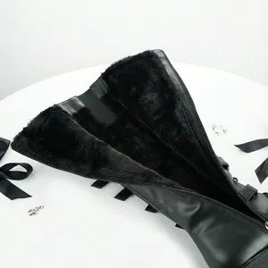 Détail de bottes hautes punk noires avec doublure en fausse fourrure et boucle coeur