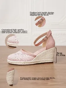 Detalle de sandalias de cuña tipo alpargata rosa con bordado floral y tira al tobillo.