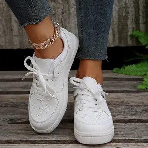 Modische weiße Damen-Sneaker mit minimalistischem Schnürdesign auf Holzgrundlage.