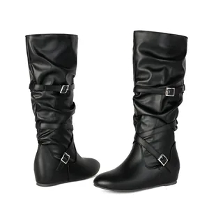 Detail view of black slouchy mid-calf boots with stylish buckle straps and flat sole.