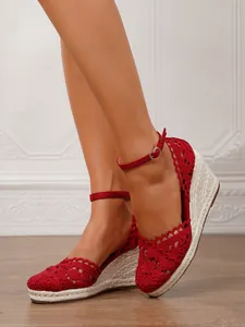 Primer plano de sandalias rojas de cuña de ganchillo con plataforma de yute y correa
