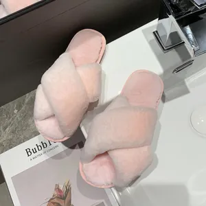 Close-up of soft pink fuzzy slippers with crossed straps placed on a white bathroom sink